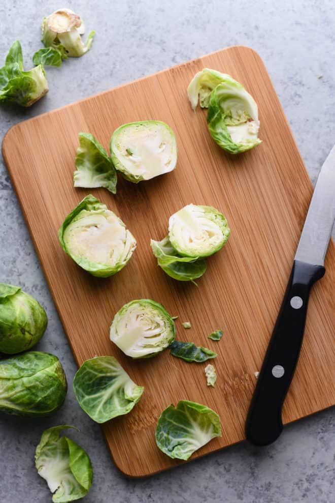 Halved green root vegetables on cutting board with paring knife.