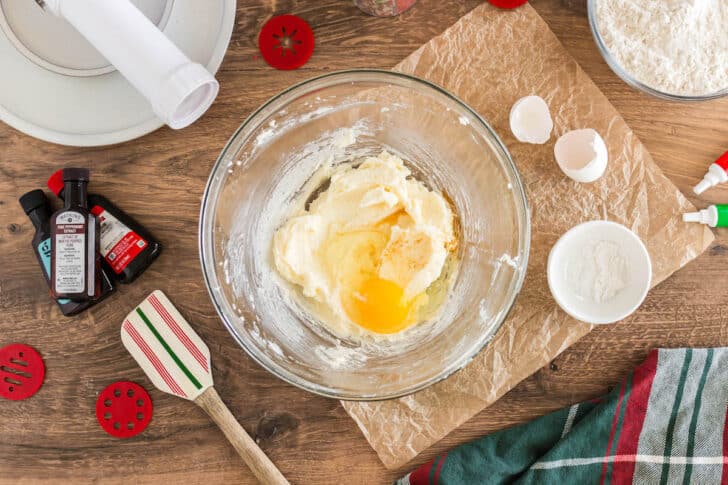 A glass bowl with a creamed mixture of butter and sugar, and a raw egg.
