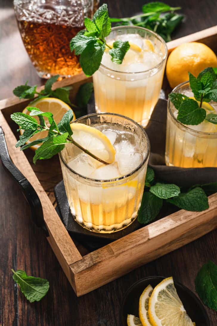 A tray filled with bourbon smash drinks garnished with mint sprigs.