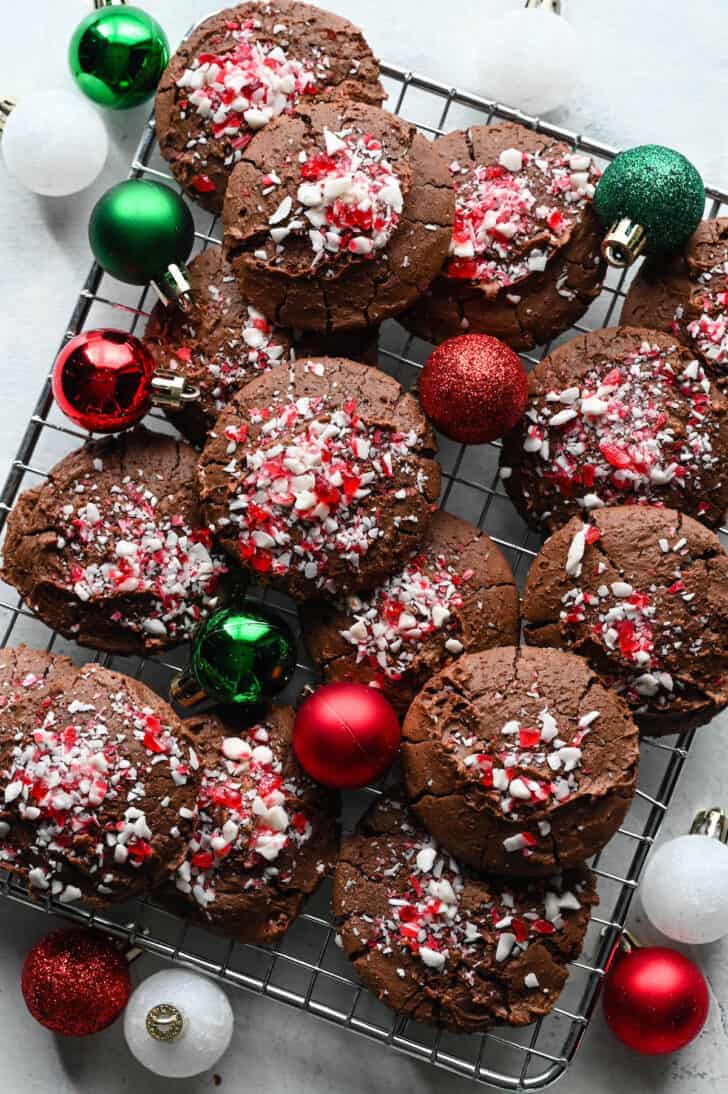 Chocolate Peppermint Cookies on a wire rack with small red, green and white bulb ornaments decorating the scene.