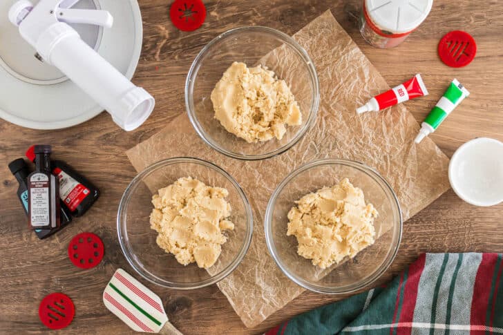 Three glass bowls filled with dough for the best spritz cookie recipe.