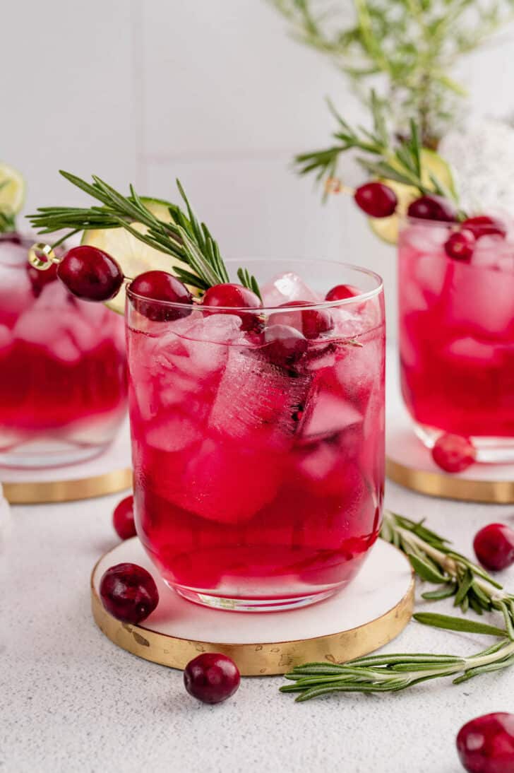 A rosemary cranberry cocktail on a light colored surface.