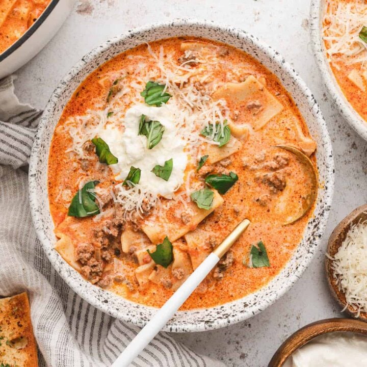 Creamy Lasagna Soup in a rustic bowl, topped with ricotta, Parmesan cheese and fresh basil.