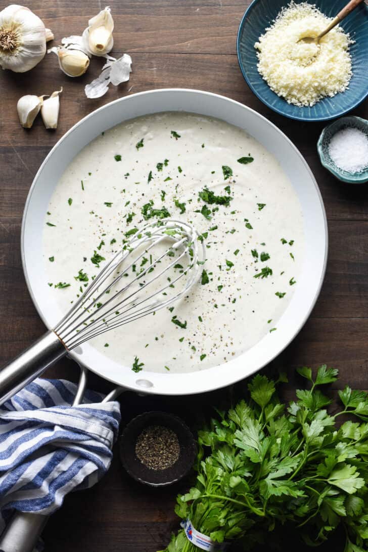 A skillet filled with a creamy white mixture topped with chopped parsley.
