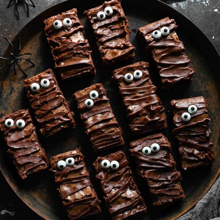 Halloween brownies that look like mummies on a rustic round tray.