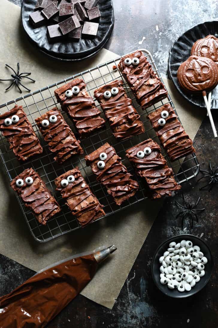 Chocolate baked goods that look like mummies on a metal cooling rack.
