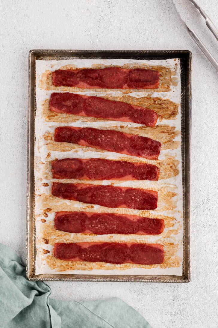 Oven baked turkey bacon slices on a rimmed baking pan.