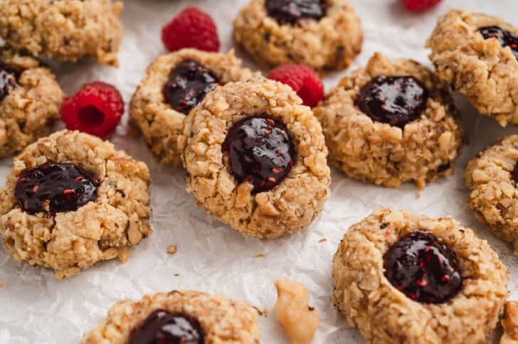 Thumbprint jam cookies on white parchment paper.