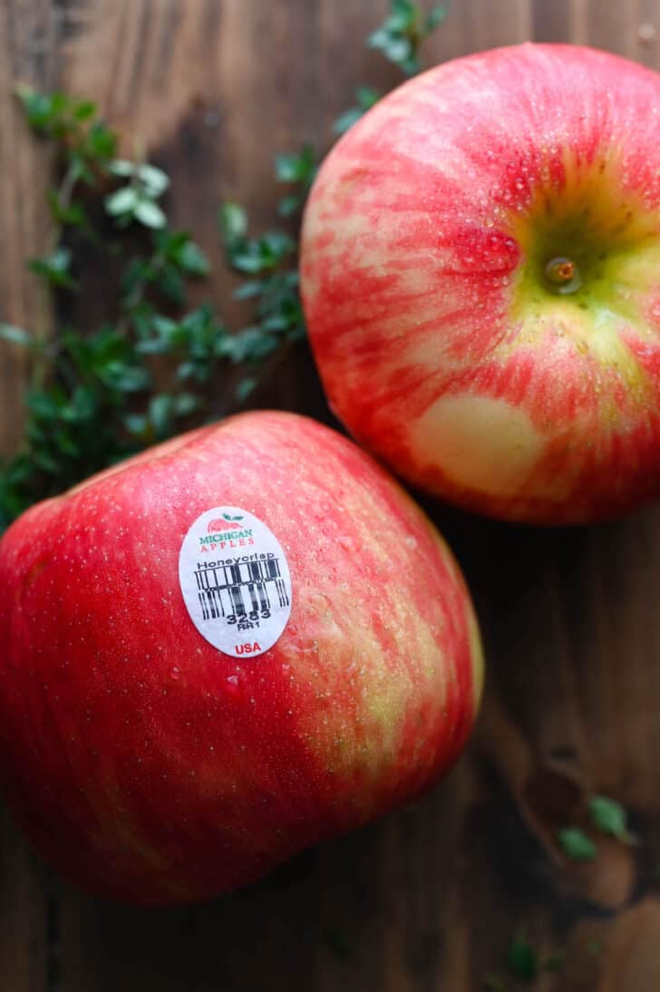 Two red and yellow hued apples with a sticker noting that they are Michigan honeycrisp apples.