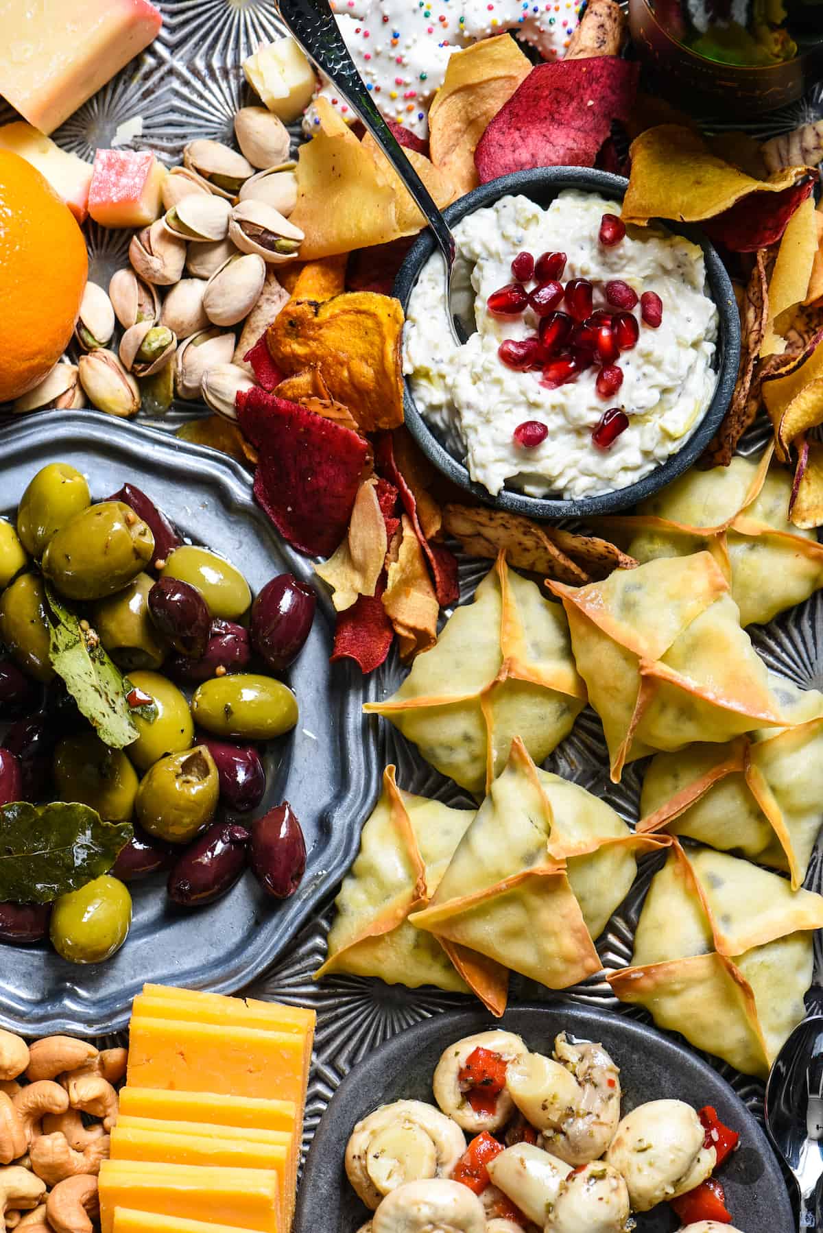 Closeup photo of platter of New Year's Eve food, focusing on wontons, olives and creamy dip.