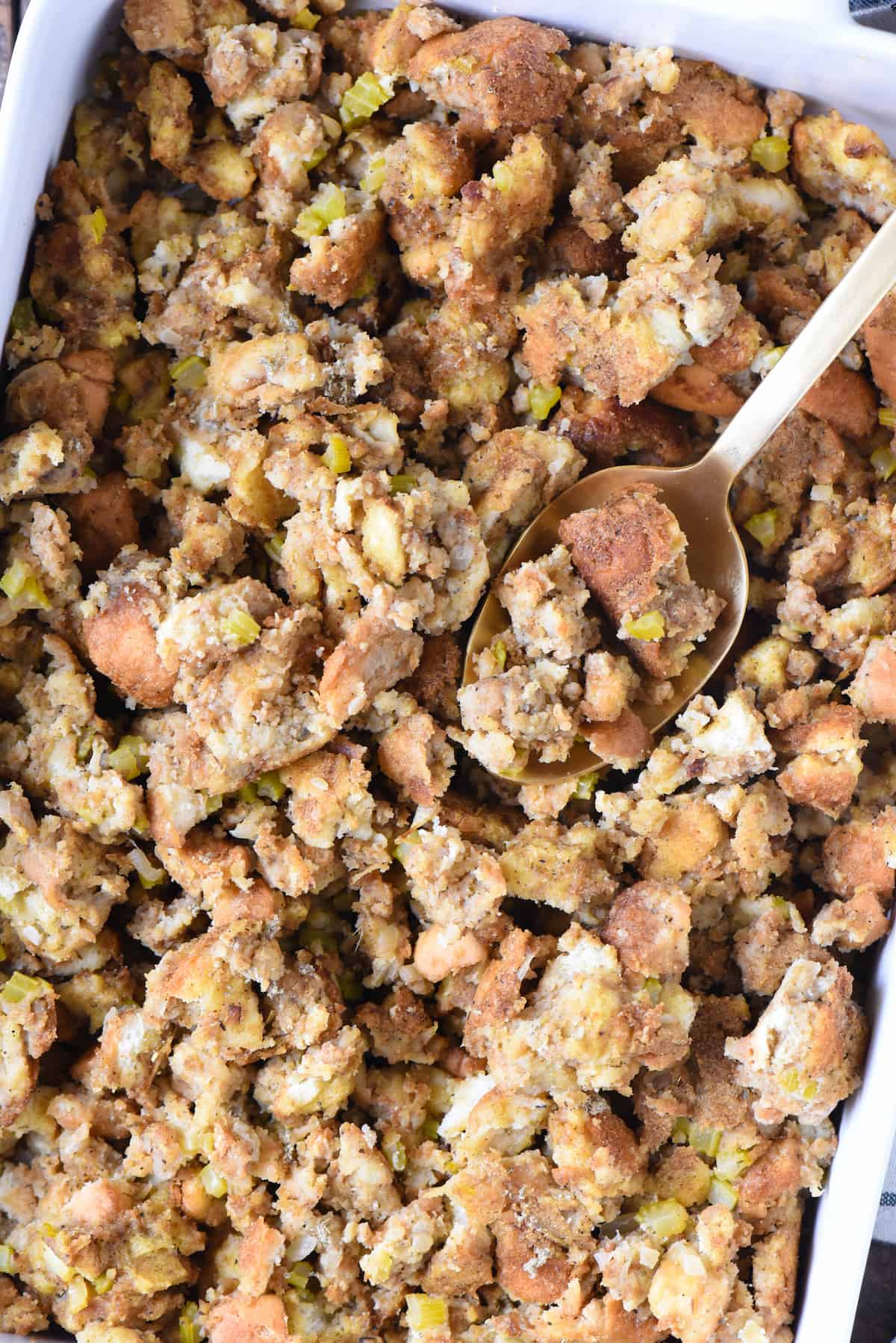 Closeup of baking dish of old fashioned bread stuffing with serving spoon.