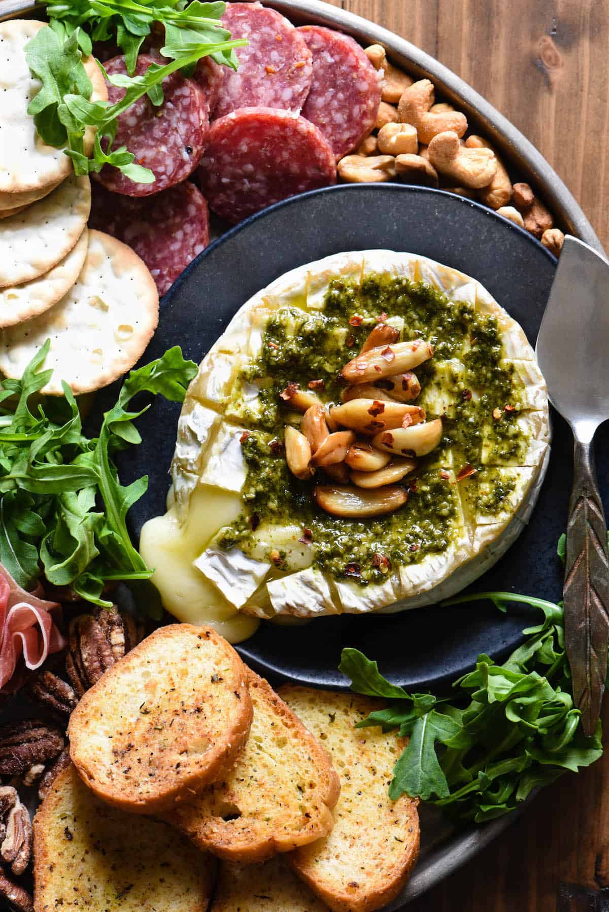 Everybody loves melted cheese, and this Savory Baked Brie takes it to the next level. Baked brie is topped with basil pesto and roasted garlic. | foxeslovelemons.com