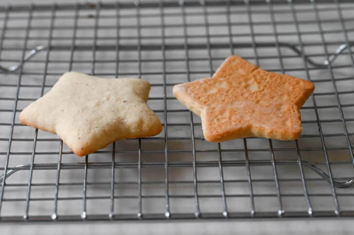Two star-shaped sour cream cookies on a cooling rack.