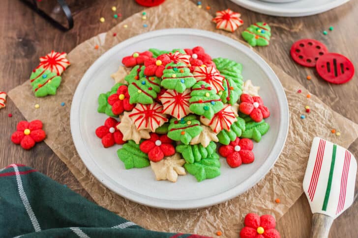 A white plate topped with red, green and white spritz cookies decorated with icing and sprinkles.